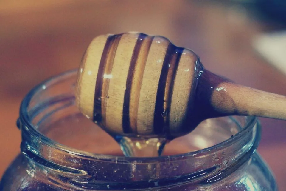 Honey in a jar with a wooden dipper